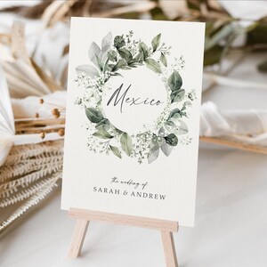 May include: A white card with a green and white floral wreath around the word "Mexico". The card also says "The wedding of Sarah & Andrew".