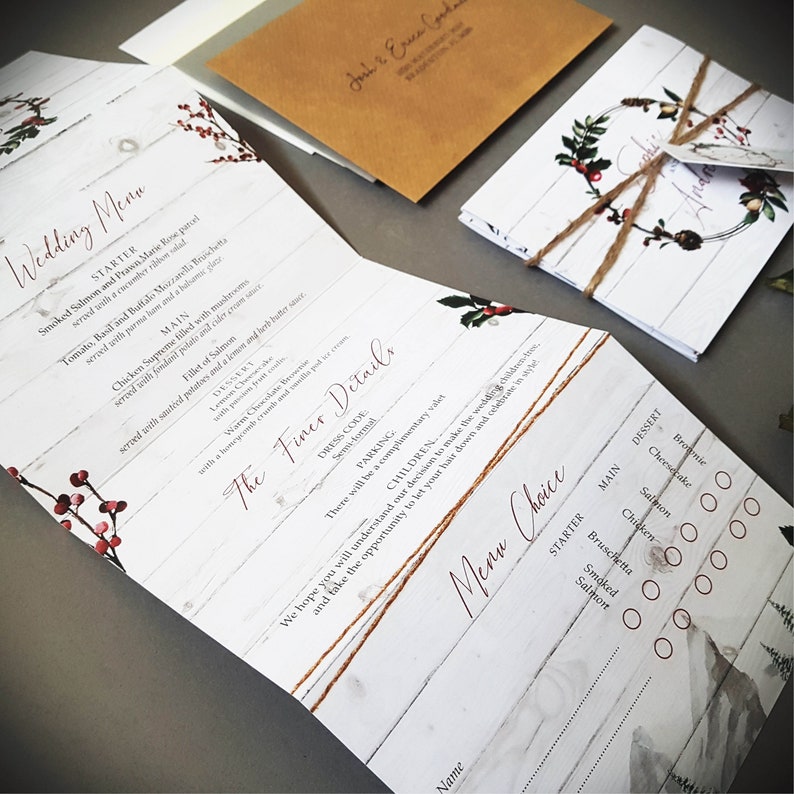 winter white wedding invitations in concertina style featuring holly and greenery with rusti twine and personalised tag. Panels include menu, menu choices, gift wish, rsvp and other finer details.