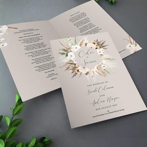 May include: A wedding ceremony order of service with a floral design featuring white flowers, dried grasses, and a beige background. The text reads "Order of Service" and "The Wedding of Sarah Coleman and Andrew Harper 8th August 2027 at Jewel Paradise Cove Beach Resort & Spa".