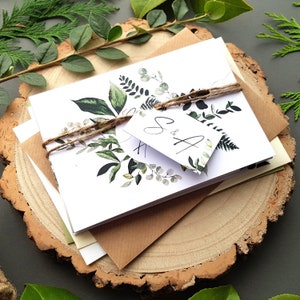 Leafy wedding invitation set with an array of greenery with a personalised tag, rustic twine and a choice of envelopes. Leafy wreath wedding invitations with iniitals