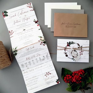 winter white wedding invitations in concertina style featuring holly and greenery with rusti twine and personalised tag. Panels include menu, menu choices, gift wish, rsvp and other finer details.