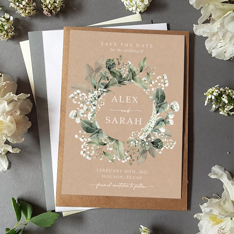 K&ouml;nnte beinhalten: Save-the-Date-Karte mit einem floralen Kranzdesign. Die Karte ist braun mit wei&szlig;em Text, der "Save the Date for the wedding of Alex and Sarah, February 20th, 2022, Houston, Texas, formal invitation to follow." lautet.