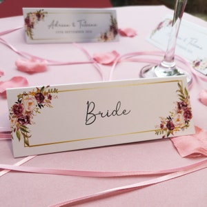 Blush gouden plaatskaart, bloemen plaatskaarten, couverts, plaatsnamen, tafelinstellingen, stoelen, tafeldecor, gastennamen en menukeuzes