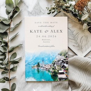 May include: A wedding invitation with the text "SAVE THE DATE" and the names "KATE & ALEX" along with the date "24.06.2026". The invitation features a scenic image of a lake and village with mountains in the background. The text "Hallstatt, Austria" is also included.