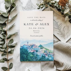 May include: A wedding invitation with the text "SAVE THE DATE" and the names "KATE & ALEX" along with the date "24.06.2026". The invitation features a watercolour painting of a hillside town with a tower.
