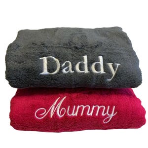 May include: Two plush towels, one gray with the word "Daddy" embroidered in white, and one pink with the word "Mummy" embroidered in white.