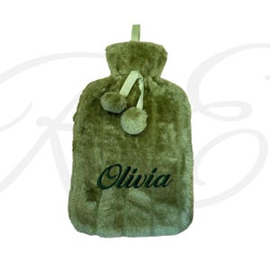 May include: Green plush hot water bottle with two pom-poms and the name "Olivia" embroidered on the front.