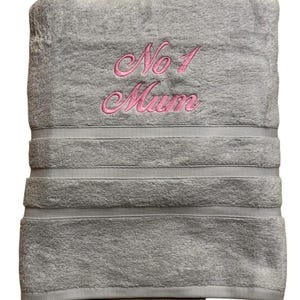 以下が含まれることがあります： ピンクの刺繍で「No 1 Mum」と書かれたグレーのバスローブです。