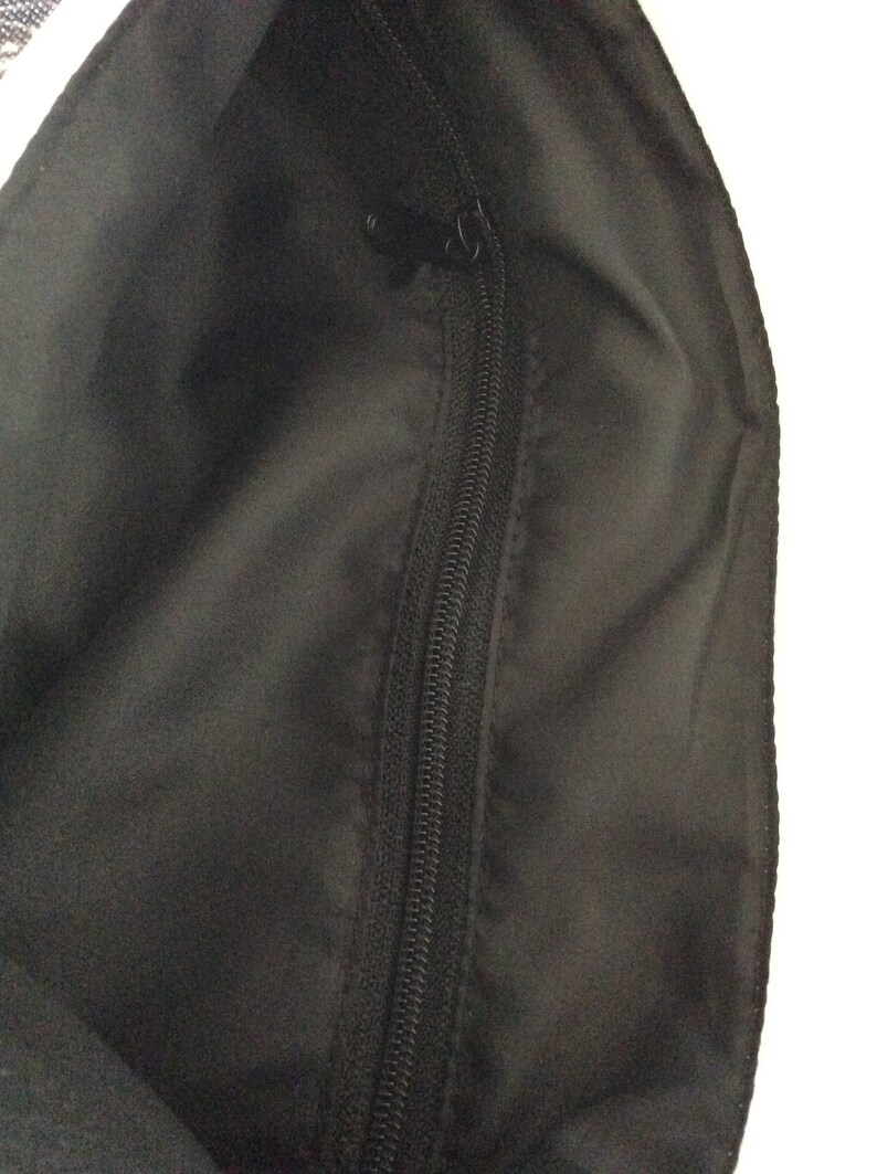 May include: Black zipper closure on the inside of a bag.