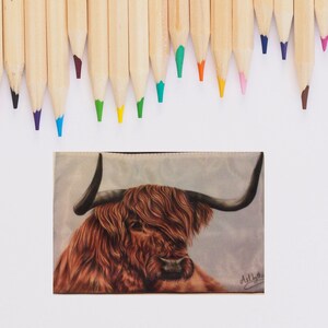 May include: A close-up of a brown and white Highland cow with long, shaggy hair. The cow is looking to the left of the image. The background is a light blue and white watercolor wash. The image is signed "ArtLyth" in the bottom right corner.