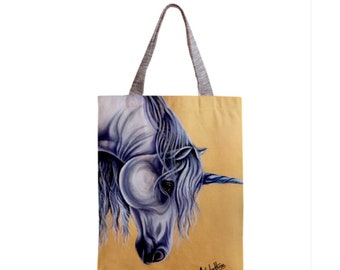 Puede incluir: Una bolsa de tela con una imagen pintada de un unicornio blanco con una crin y un cuerno azules sobre un fondo amarillo. La firma del artista está en la esquina inferior derecha.