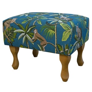 May include: A blue footstool with a tropical print featuring monkeys and palm trees. The footstool has four wooden legs.