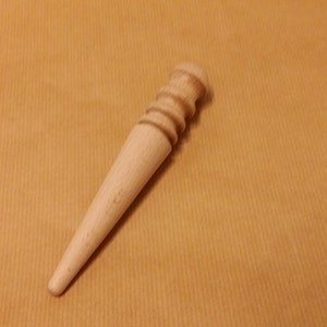 May include: A wooden leather stitching tool with a tapered point and a rounded handle with ridges.