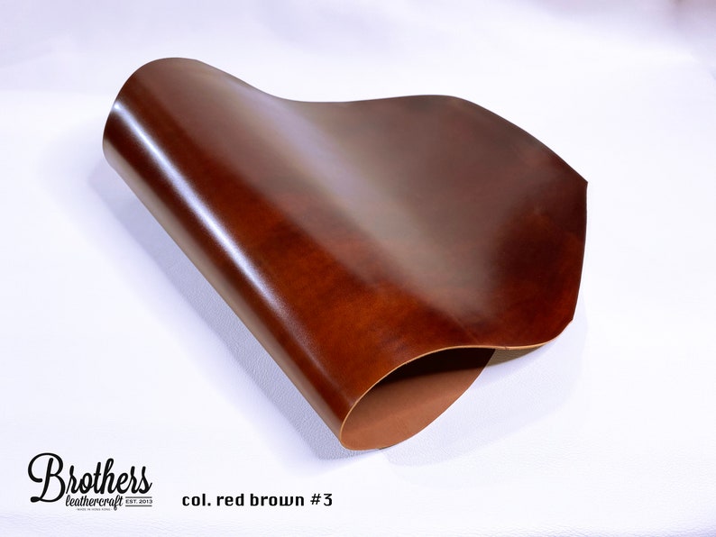 May include: A close-up of a piece of red-brown leather. The leather is folded in half and has a smooth, glossy finish. The text "col. red brown #3" is printed below the leather.