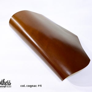 May include: A close-up of a brown leather sheet, folded in half. The leather has a smooth, polished finish. The text "col. cognac #4" is visible in the lower right corner of the image.