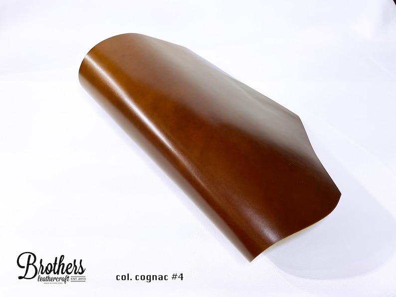 May include: A close-up of a brown leather sheet, folded in half. The leather has a smooth, polished finish. The text "col. cognac #4" is visible in the lower right corner of the image.
