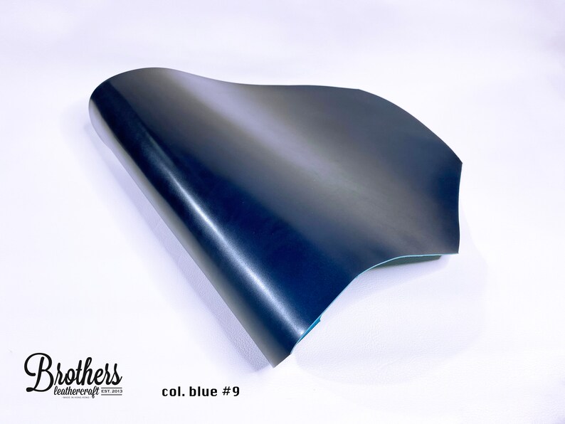 May include: A close-up of a dark blue leather sheet, folded in half, with a slight sheen. The leather is smooth and appears to be high quality. The text "col. blue #9" is visible in the lower right corner of the image.