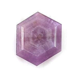 May include: A hexagonal loose gemstone with a translucent light purple hue. The stone features a flat, polished surface with visible internal geometric banding that mirrors the six-sided shape, creating a layered effect within the crystal structure.