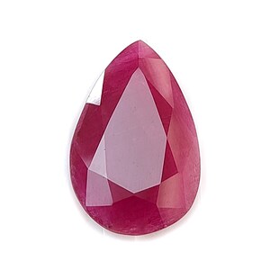 Peut inclure: Une pierre précieuse en forme de poire, de couleur rouge rubis. La gemme est d'un rouge profond et saturé, avec de multiples facettes qui réfléchissent la lumière. La pierre est posée sur un fond blanc.