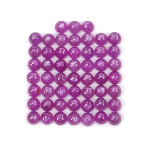 Puede incluir: Una colección de pequeñas piedras preciosas redondas de color magenta dispuestas en un patrón de cuadrícula. Cada piedra presenta una superficie lisa y pulida con una forma esférica consistente y un tono rosa violáceo intenso y vibrante.