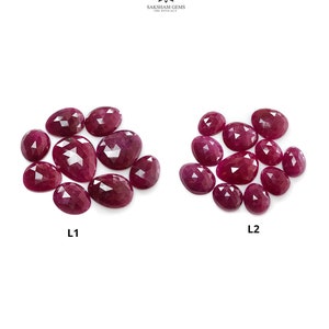 Puede incluir: Dos grupos de rubíes facetados de color rojo rosado intenso etiquetados como L1 y L2. Las piedras tienen forma ovalada y de pera con superficies reflectantes. El logotipo de Saksham Gems está en la parte superior. Piedras sueltas en dos grupos.