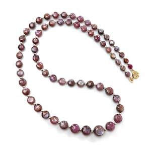 May include: A necklace featuring a strand of faceted, round, deep red gemstones with silver-colored spacers. The necklace has a gold-colored clasp and is displayed against a white background. The gemstones have a polished, reflective surface.