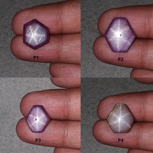 Puede incluir: Cuatro piedras preciosas de rubí estrella en varios tonos de morado y rosa. Cada piedra preciosa tiene forma hexagonal con un patrón de estrella visible. Las piedras preciosas se sostienen en una mano.