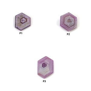 Puede incluir: Tres gemas hexagonales facetadas en tonos púrpura y lavanda se muestran sobre un fondo blanco. Cada piedra tiene un patrón hexagonal más pequeño en el centro, con líneas internas visibles.