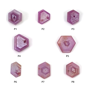 Puede incluir: Ocho gemas hexagonales facetadas de color rosa con un patrón en forma de estrella en el centro. Las gemas están etiquetadas de P1 a P8.