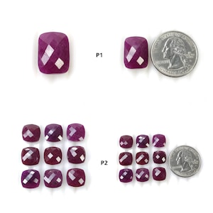 May include: Faceted, cushion-cut ruby gemstones in various sizes. The rubies are a deep red-purple hue. A US quarter coin is included for size comparison. The gemstones are arranged on a white surface.