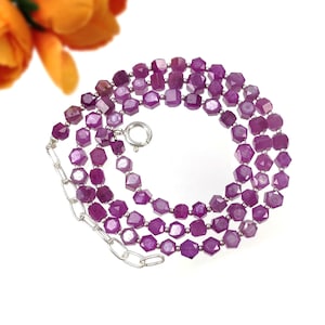 May include: A multi-strand necklace with faceted, hexagonal, deep purple gemstones. The necklace has a silver chain and clasp. The gemstones are strung together, creating a layered effect. The background is white.