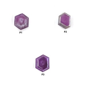 Peut inclure: Trois pierres précieuses hexagonales violettes étiquetées P1, P2 et P3. Chaque pierre présente une surface à facettes distincte avec des nuances variées de violet et de magenta. Les pierres sont disposées sur un fond blanc uni, mettant en valeur leurs formes géométriques.