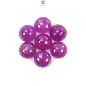 Op de afbeelding: Zeven ronde, paarse edelstenen, waarschijnlijk amethist of robijn, met een gladde, gepolijste afwerking. De edelstenen zijn in een cluster op een witte achtergrond gerangschikt.