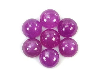 Puede incluir: Siete piedras preciosas redondas de color púrpura, probablemente amatista o rubí, con un acabado liso y pulido. Las piedras preciosas están dispuestas en un racimo sobre un fondo blanco.