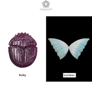 May include: Two carved gemstone pendants, one shaped like a scarab beetle in a deep purple color and the other shaped like a butterfly in a light blue and white color. The scarab beetle pendant is labeled "Ruby" and the butterfly pendant is labeled "Larimar".