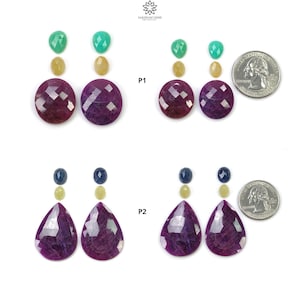 May include: Assortment of faceted gemstones in various shapes and colors, including oval, teardrop, and round. The gemstones are arranged in pairs with a quarter coin for size comparison. The colors include deep red, yellow, green, and blue.