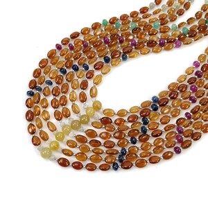 May include: A strand of oval-shaped gemstone beads in shades of brown, yellow, blue, green, and pink. The beads are strung on a silver wire.