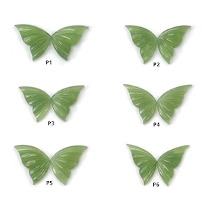 Könnte beinhalten: Sechs grüne Jade-Anhänger in Form von Schmetterlingen, jeder mit einem anderen Muster und einer anderen Textur. Die Anhänger sind mit P1 bis P6 beschriftet.