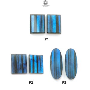May include: Six polished labradorite gemstones arranged in three pairs labeled P1, P2, and P3. The stones feature a dark gray base with vibrant, vertical electric blue chatoyant stripes. Two are rectangular, two are square, and two are oval.