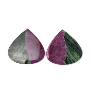 May include: Two pear-shaped ruby zoisite cabochons featuring a distinct color split. Each stone displays a vibrant magenta-pink center section contrasted by deep forest green and black mineral inclusions, polished to a smooth, reflective finish.