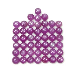 Puede incluir: Una colección de cuarenta y tres piedras preciosas cabujón redondas, pulidas y de color magenta dispuestas en un patrón de cuadrícula. Cada piedra presenta una superficie lisa y abovedada con un sutil reflejo de luz estelar.
