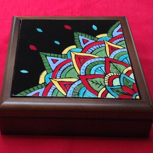 May include: A wooden box with a black and colorful mandala design on the lid. The mandala features red, green, blue, yellow, and white colors.