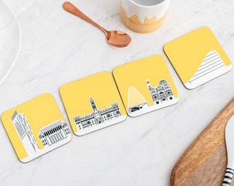 May include: Four yellow square coasters with black and white city skyline designs. The coasters feature the text "Chester" on one of the coasters.