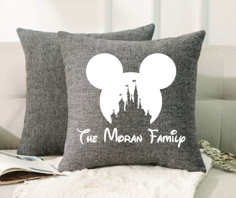 May include: Two gray throw pillows with a white silhouette of Mickey Mouse's head with the iconic Disney castle inside. The text "The Moran Family" is printed below the silhouette.