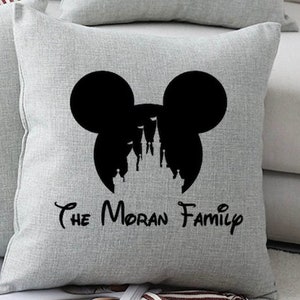 May include: A gray throw pillow with a black silhouette of Mickey Mouse ears and the Disney castle inside. The text "The Moran Family" is printed below the silhouette.