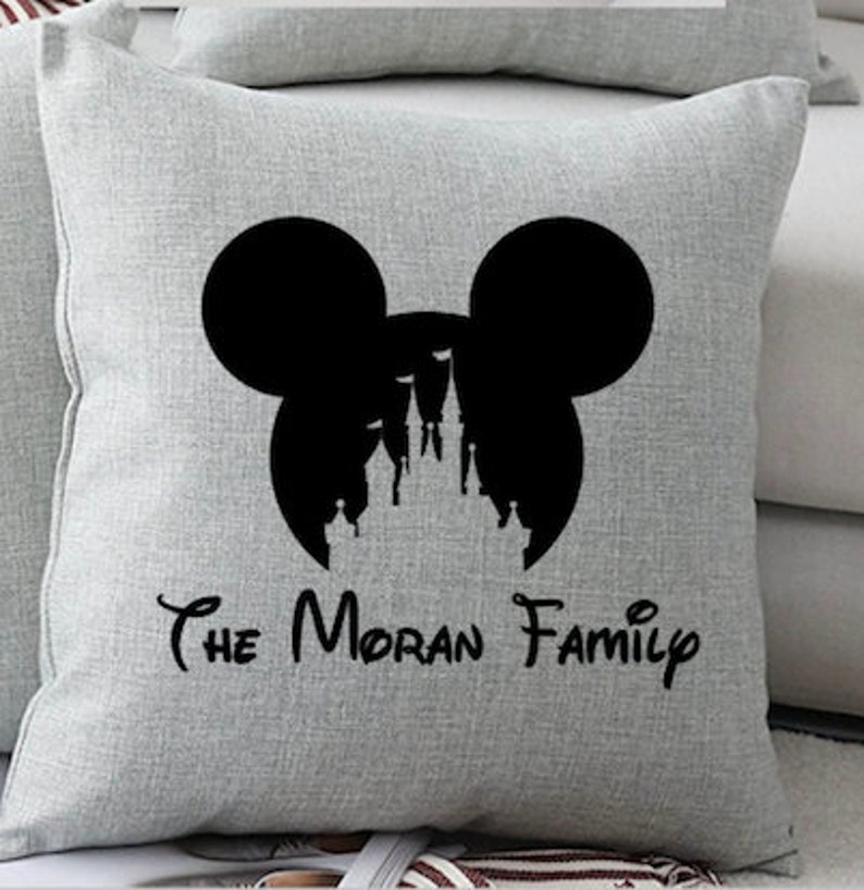 May include: A gray throw pillow with a black silhouette of Mickey Mouse ears and the Disney castle inside. The text "The Moran Family" is printed below the silhouette.