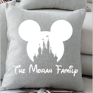 May include: Gray throw pillow with a white silhouette of Mickey Mouse ears and Cinderella's castle inside the ears. The text "The Moran Family" is printed below the silhouette.
