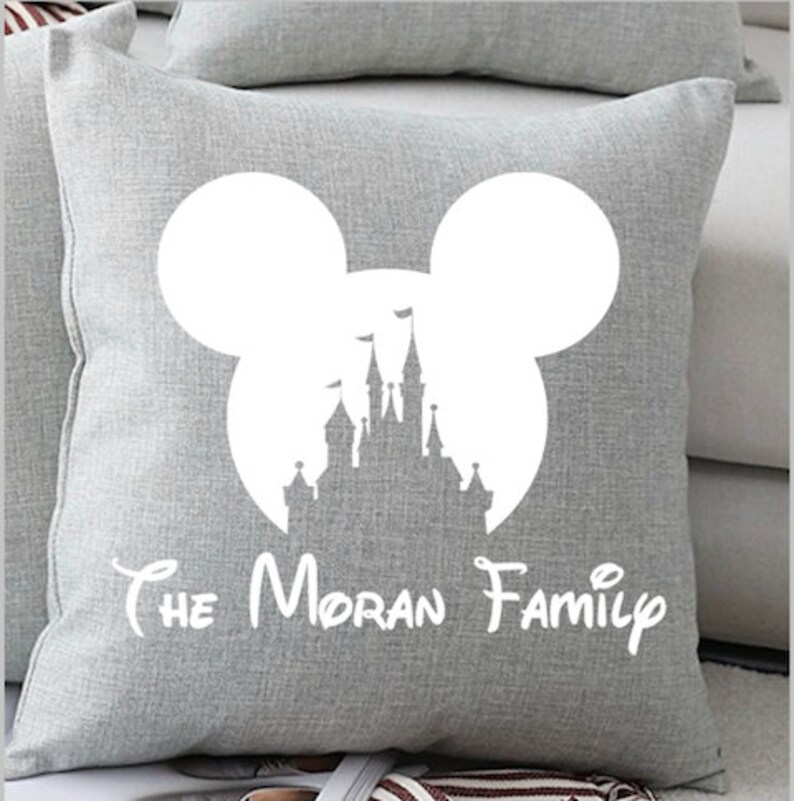 May include: Gray throw pillow with a white silhouette of Mickey Mouse ears and Cinderella's castle inside the ears. The text "The Moran Family" is printed below the silhouette.
