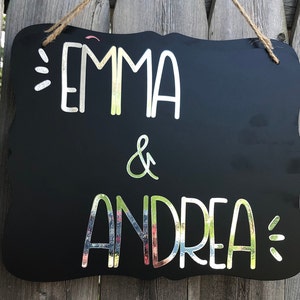 Puede incluir: Se&ntilde;al negra de pizarra con letras blancas que dice "Emma & Andrea" con acentos decorativos.