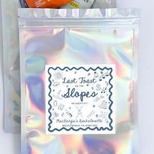 May include: A holographic, iridescent pouch labeled "Last Toast on the Slopes Recovery Kit" for MacKenzie's Bachelorette. The pouch contains Tide to Go wipes, Advil, and Liquid IV packets. The image is on a white background.